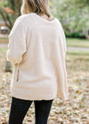 Back view of blonde model is soft cream cardigan and black pants..