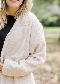 Detail view of Blonde model is soft cream cardigan.