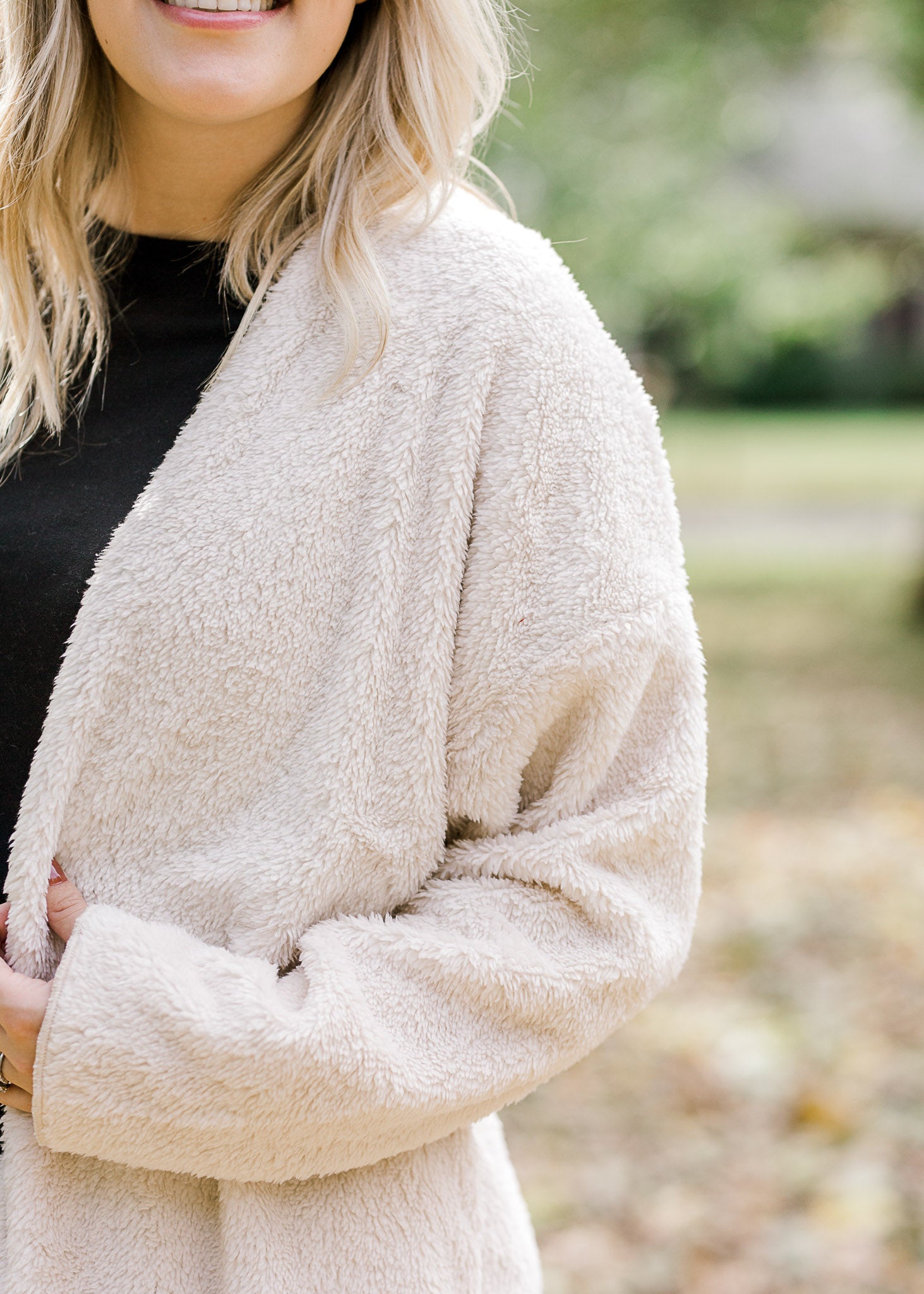 Detail view of Blonde model is soft cream cardigan.