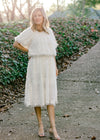 Blonde model wearing ivory colored faux feather skirt with heels.
