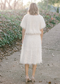 BAck view of Blonde model wearing ivory colored faux feather skirt.