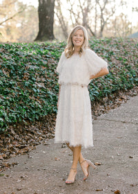 Blonde model wearing ivory colored faux feather skirt.