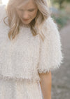 Close up of Blonde model wearing ivory colored faux feather skirt.