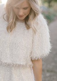 Close up of Blonde model wearing ivory colored faux feather skirt.