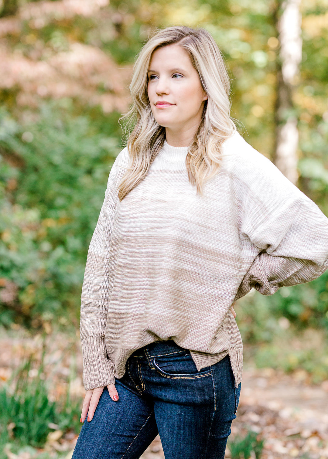 Blonde model wearing a cream to taupe transition sweater. 