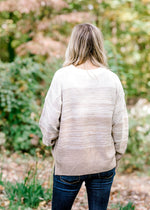 Back view of Blonde model wearing a cream to taupe transition sweater. 
