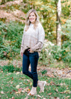 Blonde model wearing a cream to taupe transition sweater with jeans and booties.