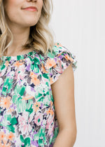 Close up view of ruffle sleeve on Blonde model wearing a abstract floral top.