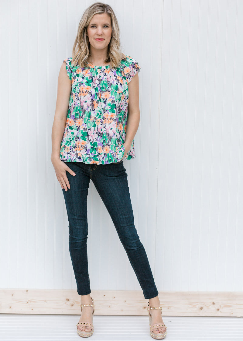 Blonde model wearing a abstract floral top with dark jeans.