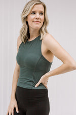 Blonde model wearing a hunter green workout top.