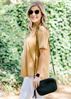 Blonde model wearing black sunglasses and carrying a black purse. 