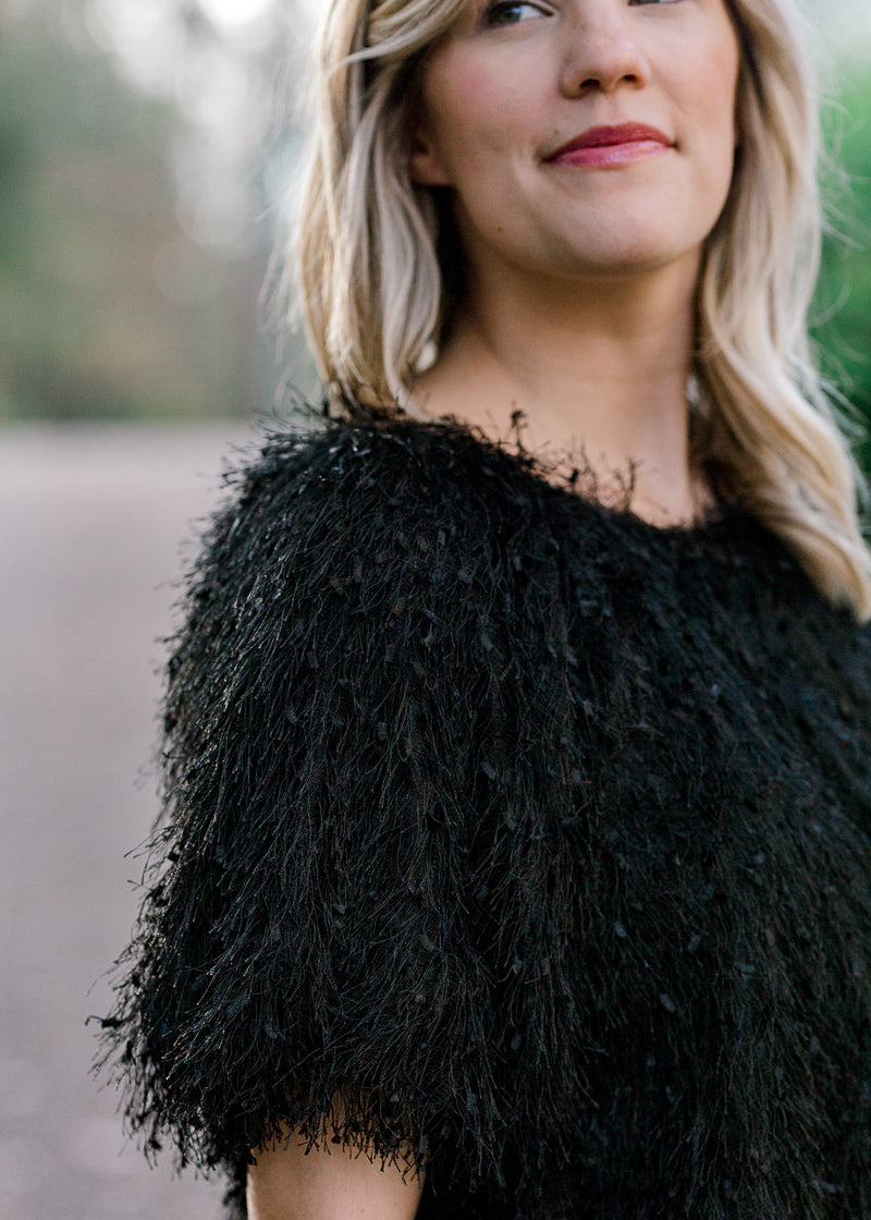 Close up of Blonde model wearing black faux feather skirt and top.