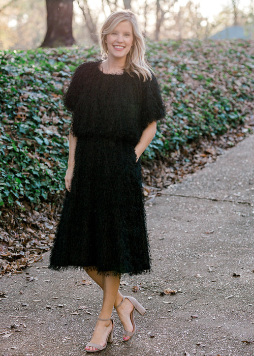 Blonde model wearing black faux feather skirt and top.