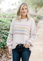 Blonde model wearing cream sweater with stripes.