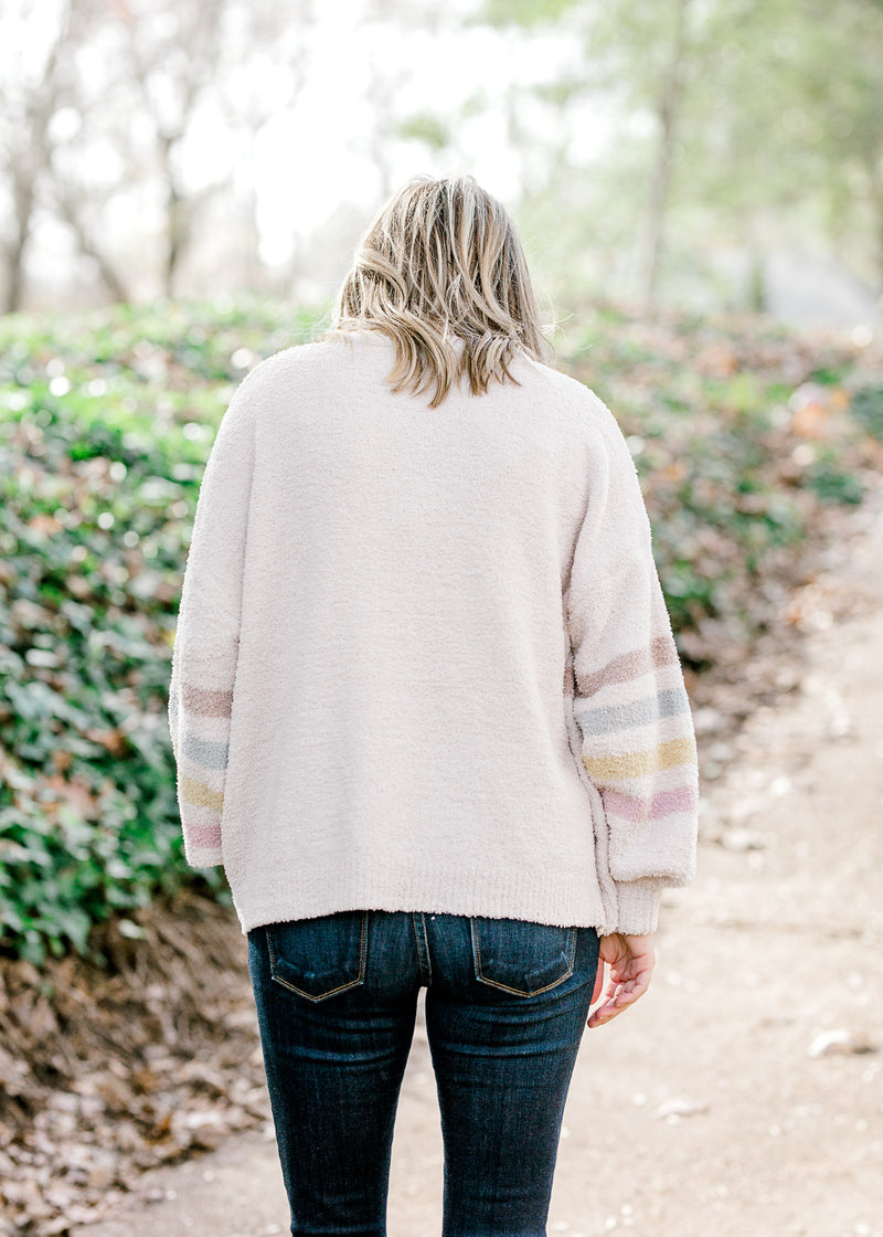 Back view of Blonde model wearing cream sweater with stripes.