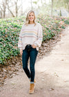 Blonde model wearing cream sweater with stripes with jeans and booties.