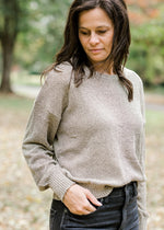 Brunette model wearing taupe sweater with gold shimmer detail.