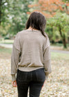 Back view of Brunette model wearing taupe sweater with gold shimmer detail.