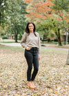 Brunette model wearing taupe sweater with gold shimmer detail with black jeans and mules.
