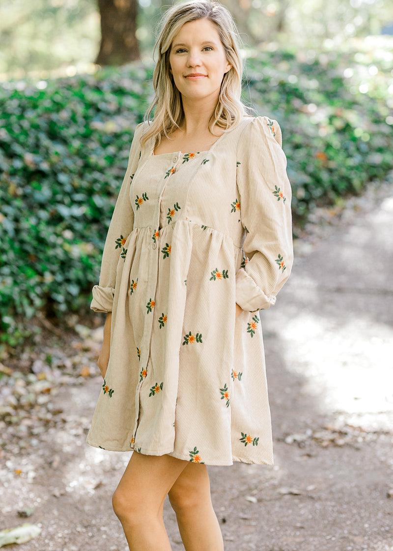 Blonde model wearing cream corduroy dress with sunflower embroidery.