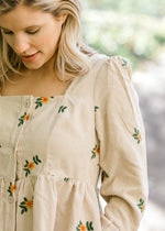 Close up view of sunflower embroidery on cream dress.