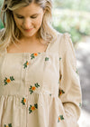 Detail view of corduroy, button-up dress with sunflower embroidery. 