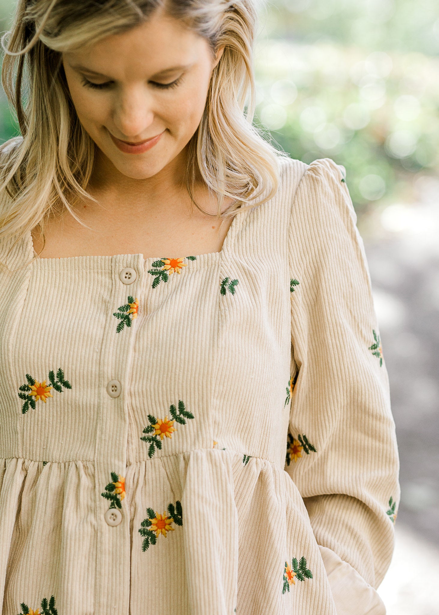 Detail view of corduroy, button-up dress with sunflower embroidery. 