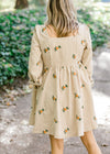 Back view of Blonde model wearing cream corduroy dress with sunflower embroidery.