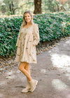 Blonde model wearing cream corduroy dress with sunflower embroidery and booties.