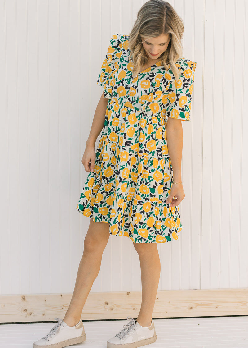 Model wearing an abstract, floral, above the knee dress with sneakers. 