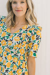 Close up of button closure on Model wearing an abstract, floral, above the knee dress. 