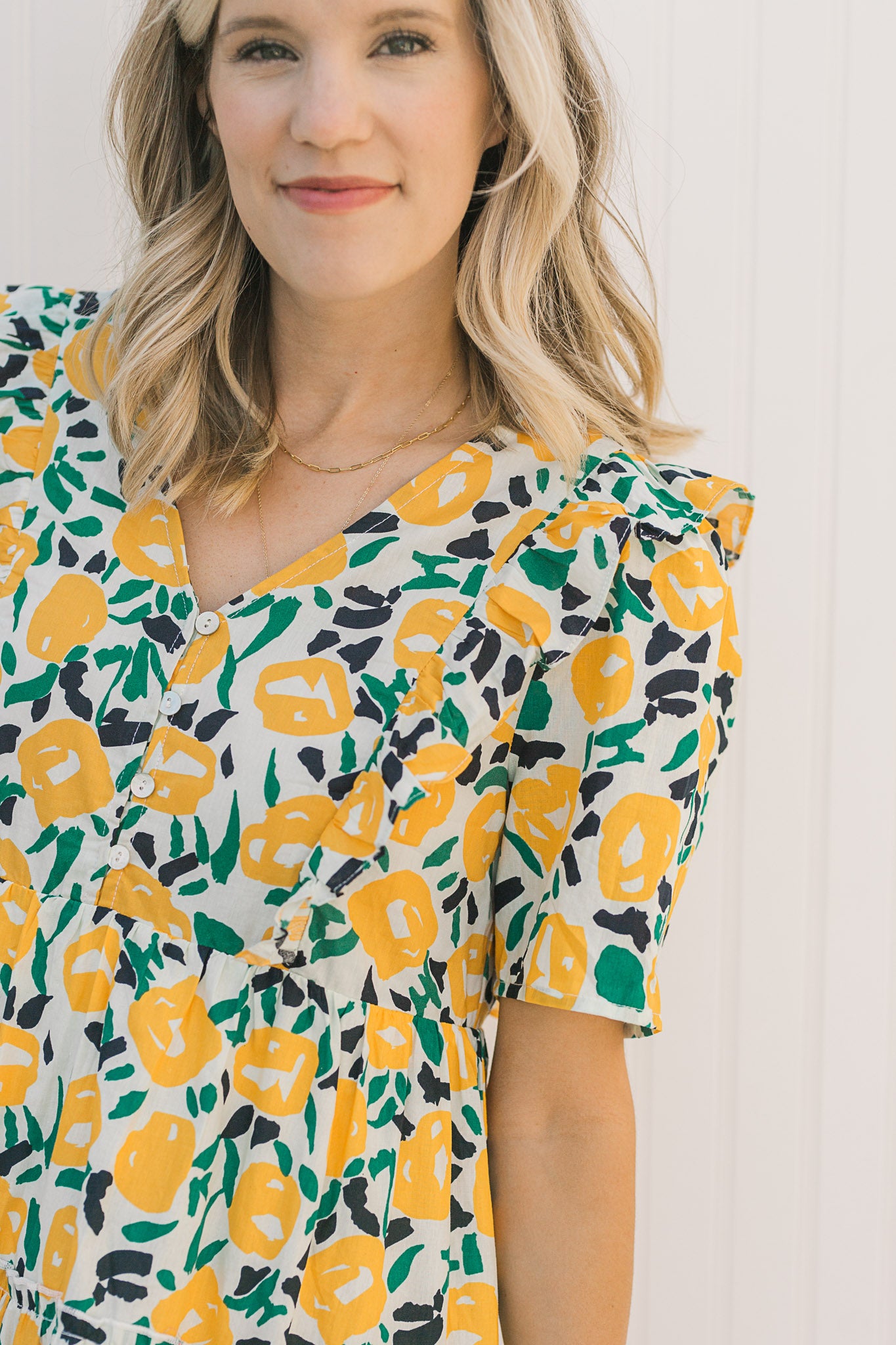Close up of button closure on Model wearing an abstract, floral, above the knee dress. 