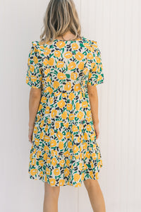 Back view of Model wearing an abstract, floral, above the knee dress with sneakers.