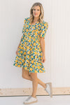 Model wearing an abstract, floral, short sleeve  dress with sneakers.