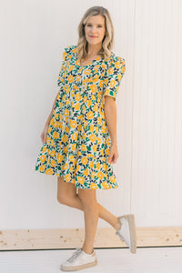 Model wearing an abstract, floral, short sleeve  dress with sneakers.