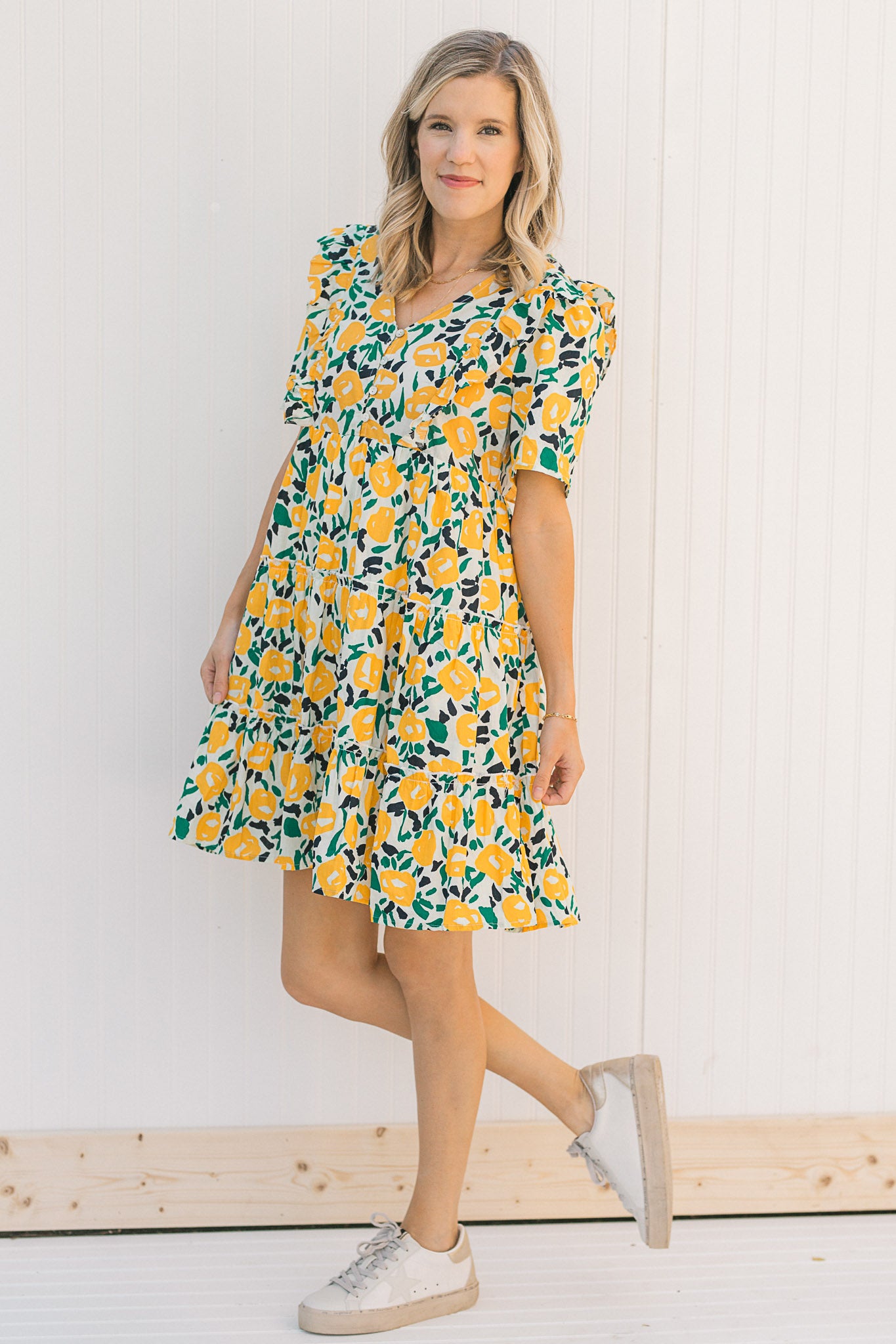 Model wearing an abstract, floral, short sleeve  dress with sneakers.