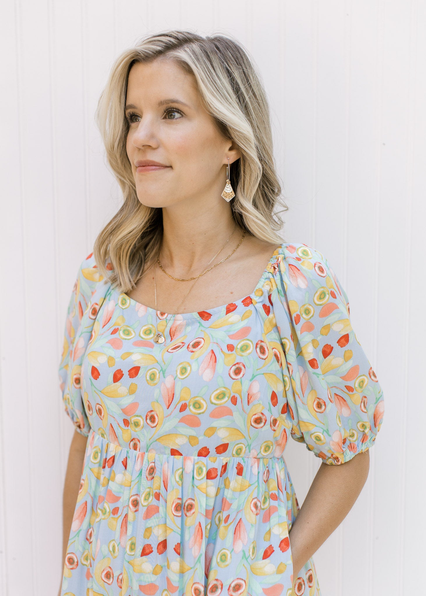 Close up view of bubble short sleeves and square neckline on a light blue dress with a floral design