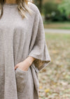 Close up of sleeve and pocket detail on model wearing taupe poncho.