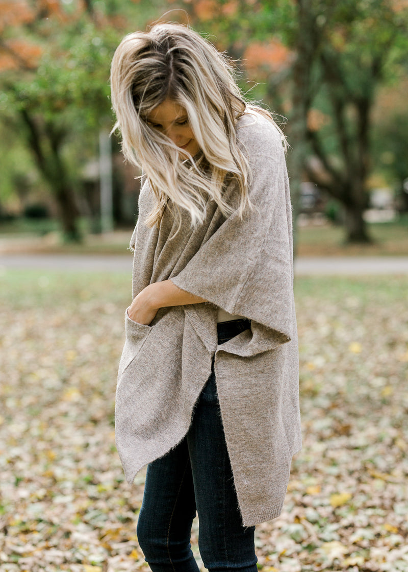 Side slit view of Blonde model wearing taupe poncho. 