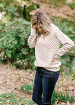 Blonde model wearing a taupe and cream zig zag sweater. 