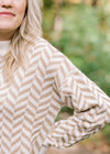 Close up view of blonde model wearing a taupe and cream zig zag sweater.