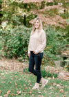 Blonde model wearing a taupe and cream zig zag sweater with jeans and booties.