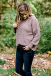 Blonde model wearing taupe sweater with jeans.