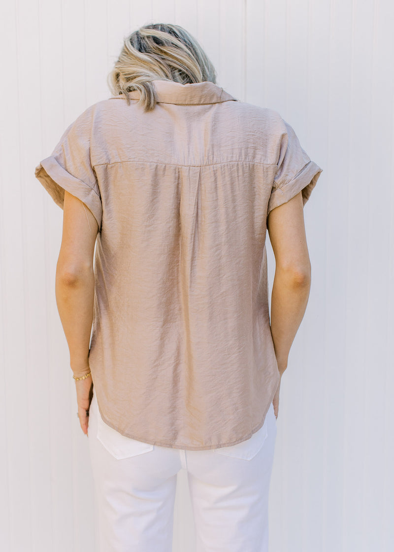Back view of Model wearing a taupe v-neck top with chest pockets and cuffed short sleeves. 