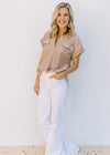Model wearing a tan top with high waist, white denim, flare jeans with a frayed waist and raw hem. 