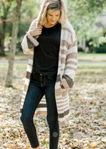 Blonde model wearing a cream, taupe and brown striped cardigan. 