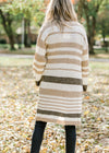 Back view of Blonde model wearing a cream, taupe and brown striped cardigan. 