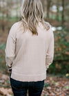 Back view of Blonde model wearing a taupe sweater with a cowl neck. 