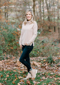 Blonde model wearing a taupe sweater with jeans and booties. 