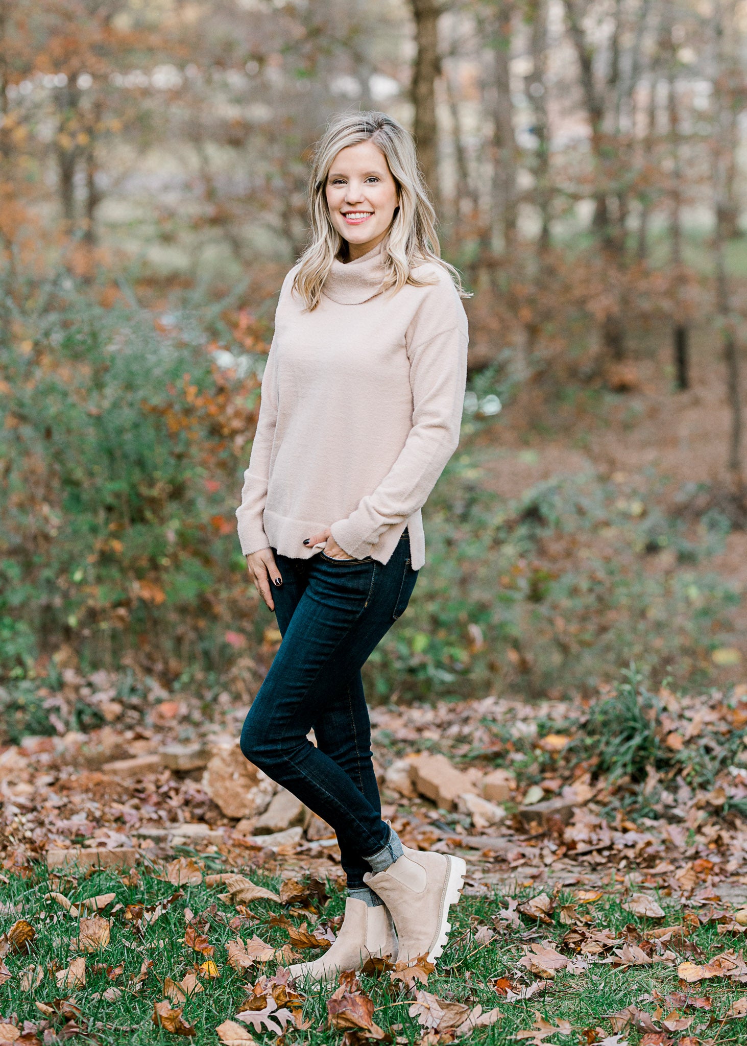 Blonde model wearing a taupe sweater with jeans and booties. 